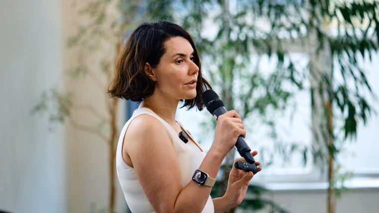 A speaker holding a microphone and a clicker while presenting at ELC meetup #15 in Brno