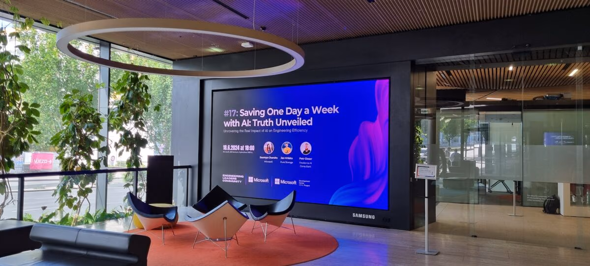 An empty venue lobby with lounge chairs under a screen announcing an Engineering Leaders Community meetup, before the doors open