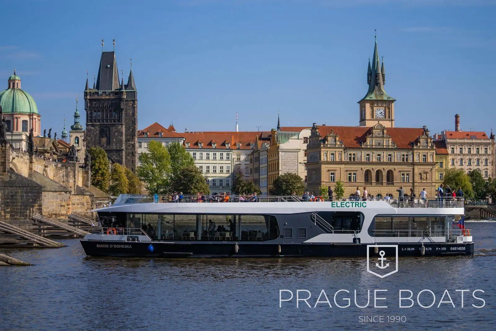 Prague Boats electric boat on the Vltava below Charles Bridge, guests on the open deck