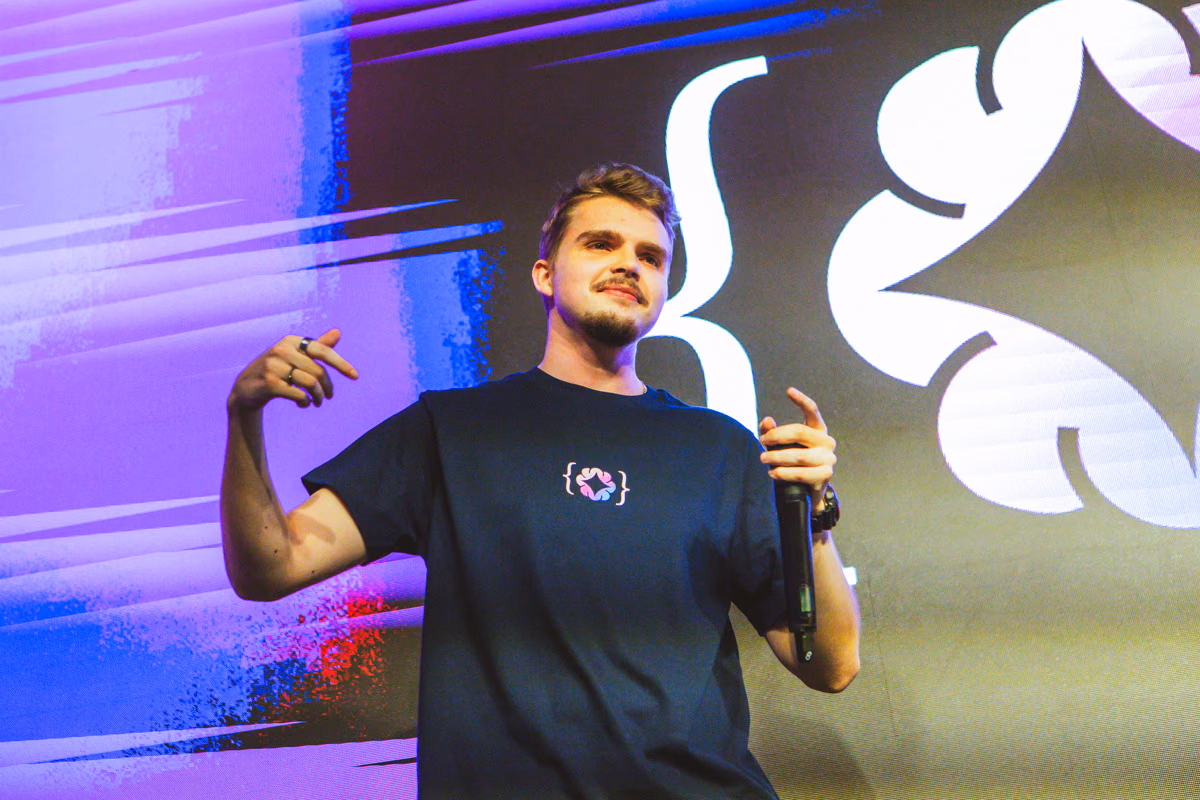 Speaker on the ELC Conference stage wearing a black T-shirt with the ELC bracket symbol on the chest