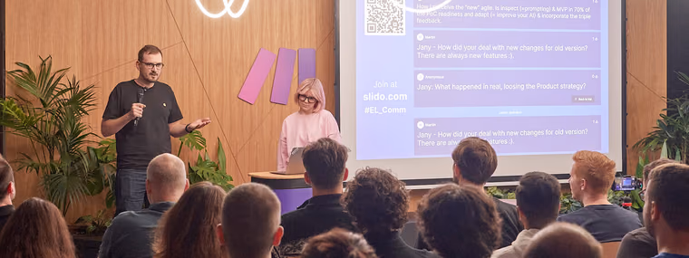 A moderator with a microphone beside a speaker at a podium running a live Q&A with an ELC audience in a wood-panelled room, the kind of questions a Chief AI Officer fields from every function.