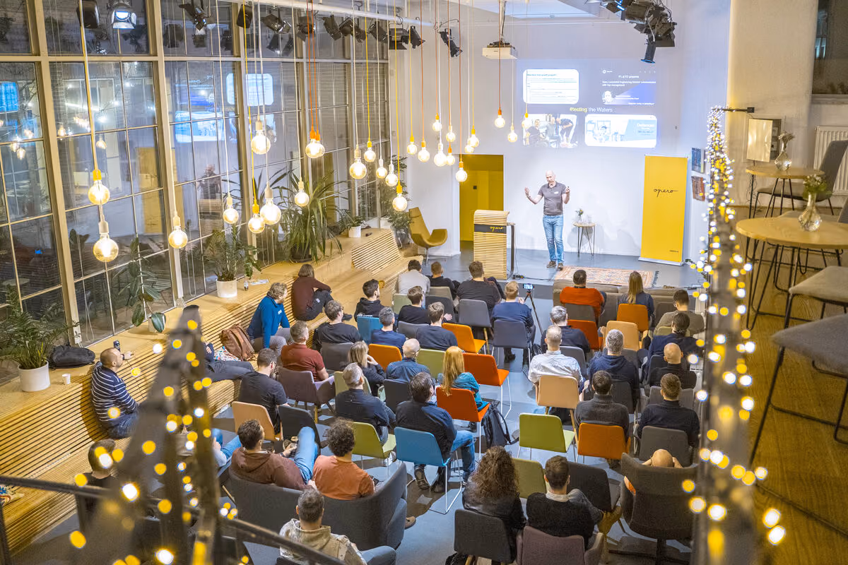 A speaker on stage at an ELC meetup, a full room of engineering leaders in front of them