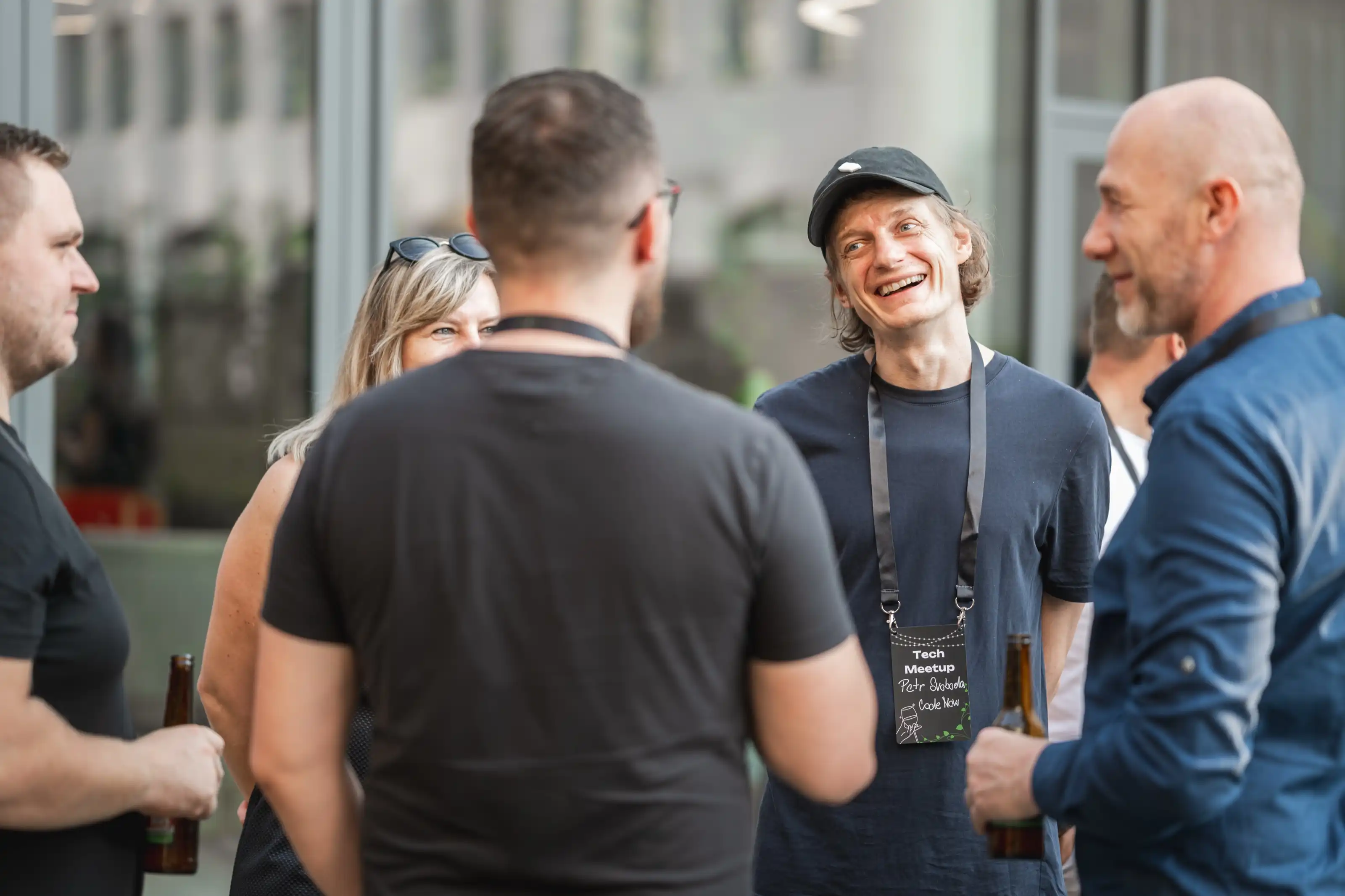 Engineering leaders networking in a small circle with drinks and conference badges at an ELC meetup.