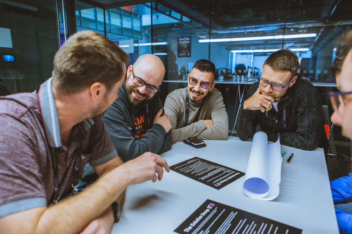 Five engineering leaders laughing over worksheets at an ELC working session, the kind of session that shapes a talk