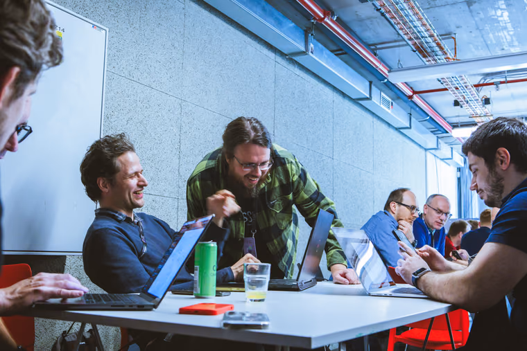 Tech leadové a IT manageři se smějí u stolu s notebooky během pracovní části akce ELC, teambuildingová aktivita v praxi