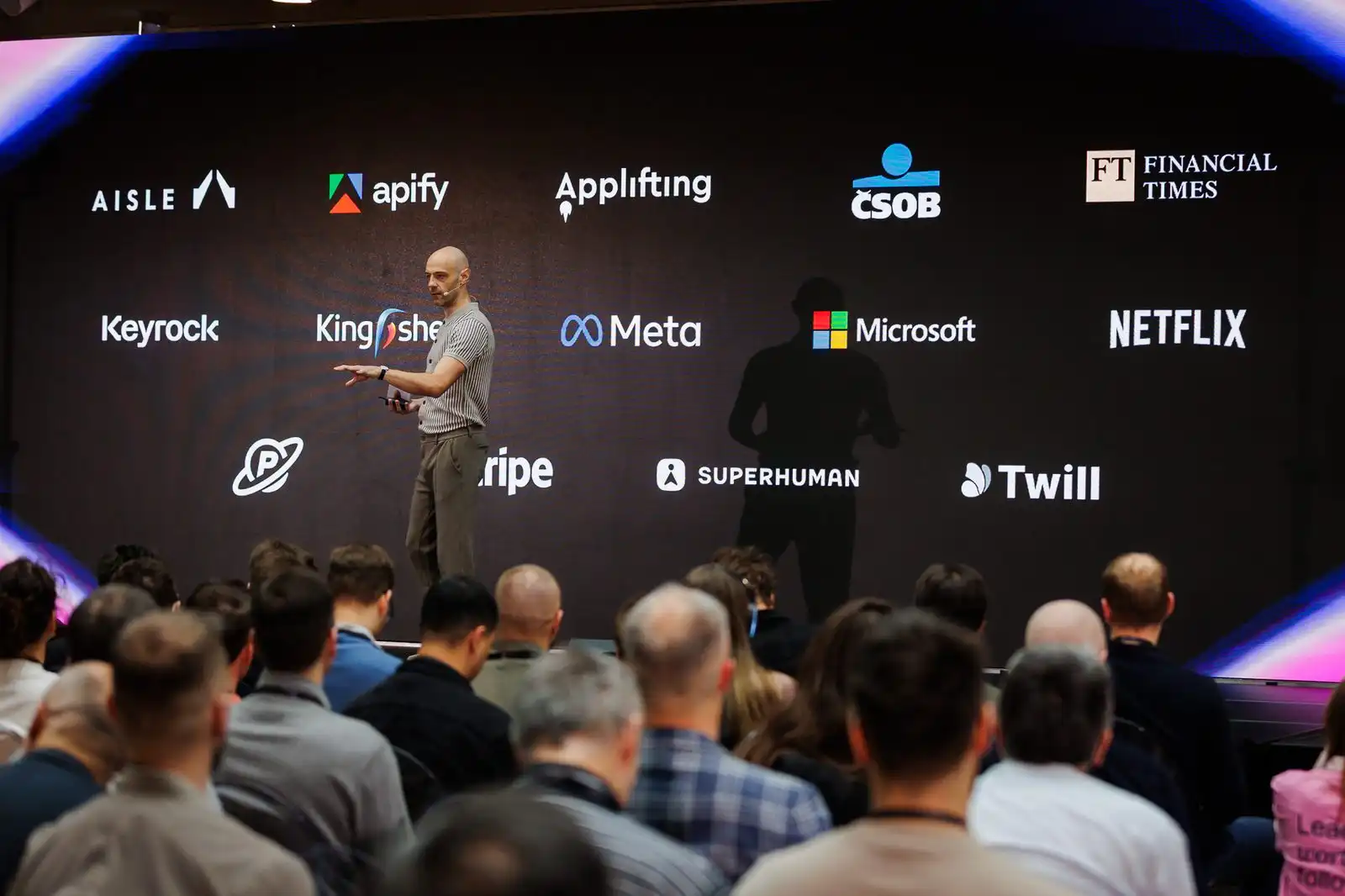 A speaker on the ELC Conference 2026 main stage in front of the partner logo wall