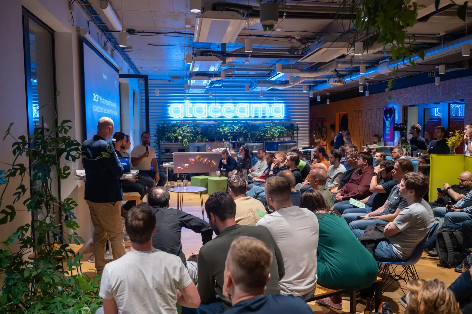 A full room at an ELC meetup hosted at Ataccama, their name lit up behind the panel.