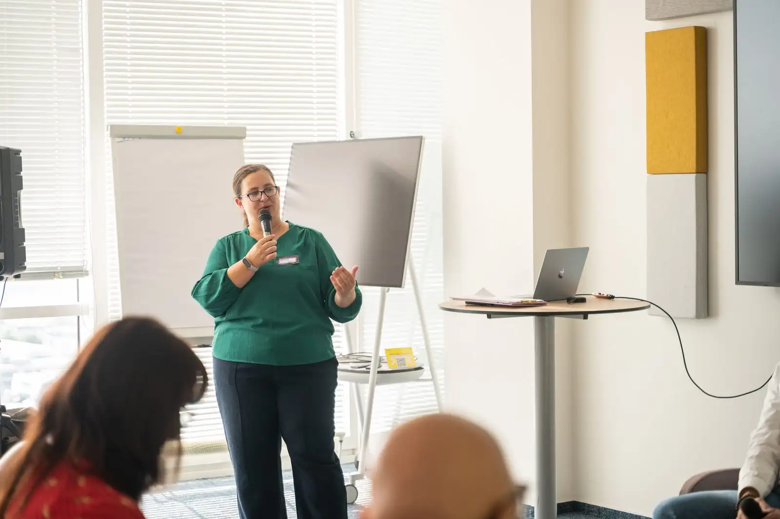 A speaker with a microphone addressing a room of leaders in a company office.