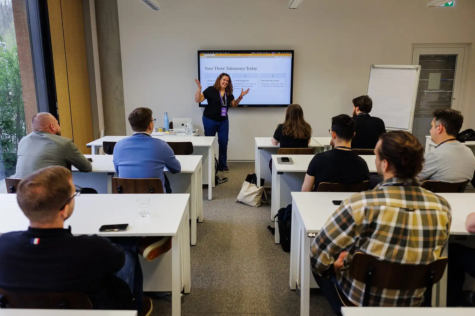 A facilitator leading a workshop for a room of leaders at desks.