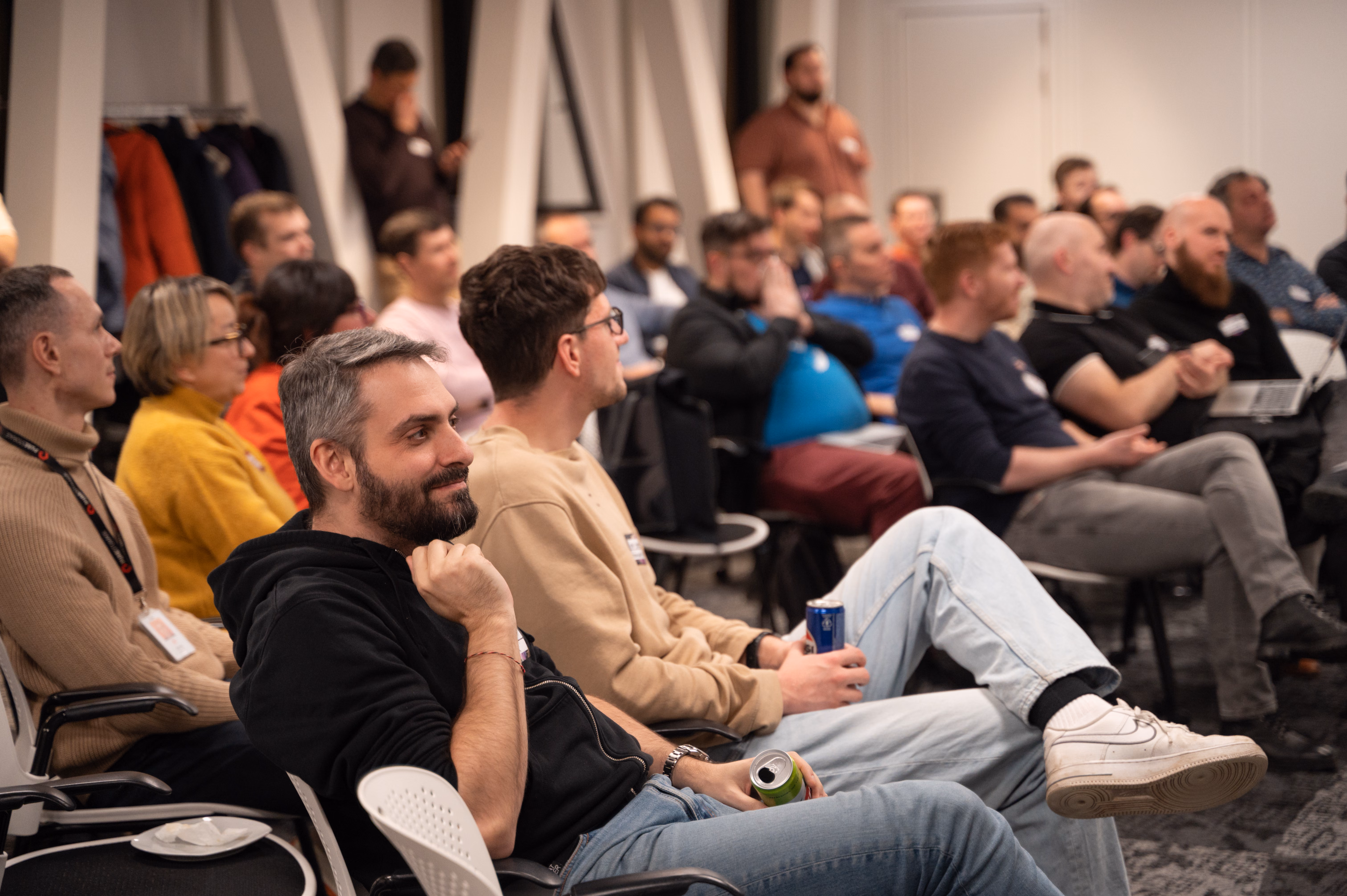 A speaker presenting on stage at ELC meetup #33 in a partner office, the audience in front of the screen