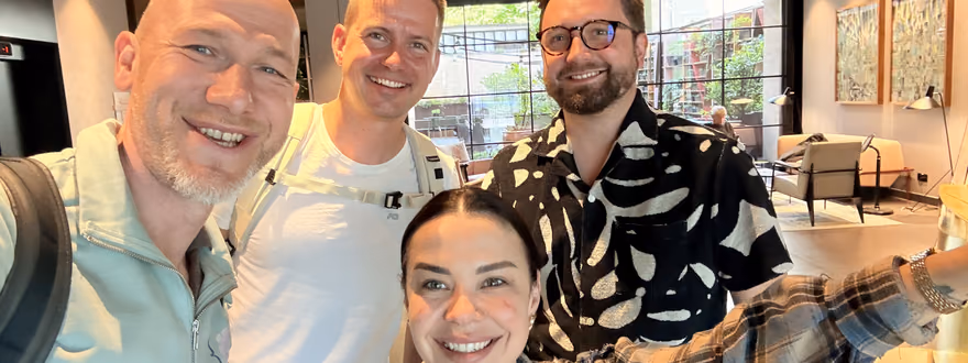 A group selfie of four attendees smiling together at the ELC meetup in Kraków