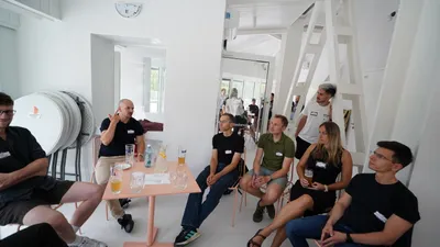 One of the three facilitated tables at ELC's Summer Party in Stromovka, Prague, with attendees seated around a small pink table mid-conversation
