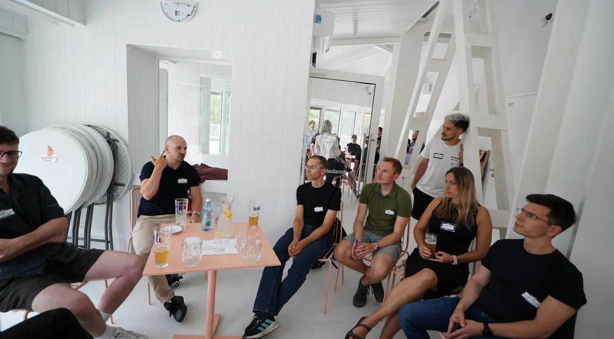 One of the three facilitated tables at ELC's Summer Party in Stromovka, Prague, with attendees seated around a small pink table mid-conversation