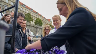 ELC speakers and guests smiling as they pick up their name lanyards at the registration table before boarding the boat on the Vltava embankment in Prague