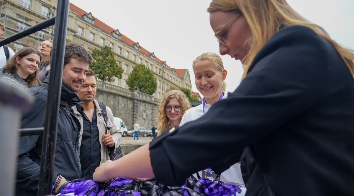 ELC speakers and guests smiling as they pick up their name lanyards at the registration table before boarding the boat on the Vltava embankment in Prague
