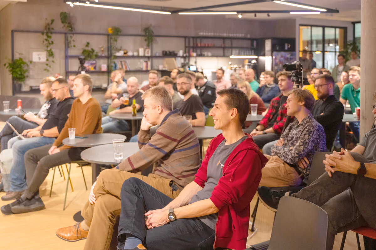A full room of engineering leaders seated for a talk at an ELC meetup hosted in a company office, a camera rig recording the stage