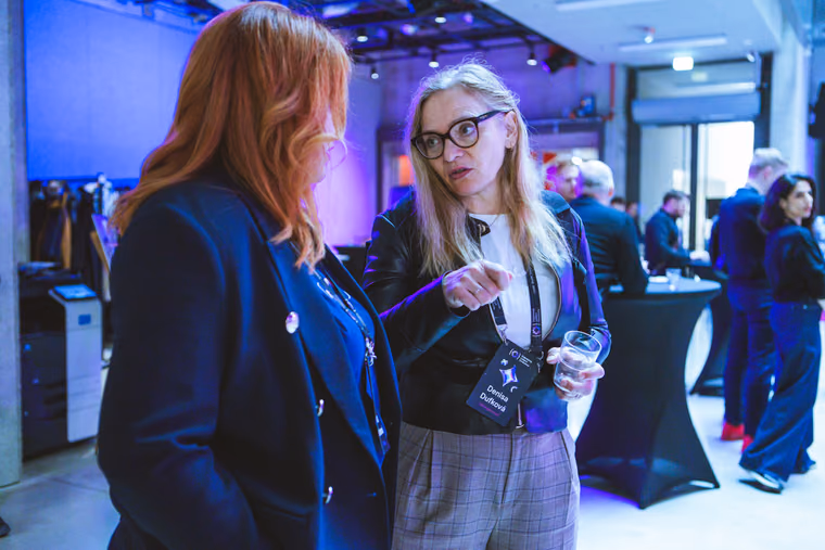 Two women in a direct, focused conversation at ELC Conference, one making her point with a raised hand, the kind of open exchange a skip-level meeting is after