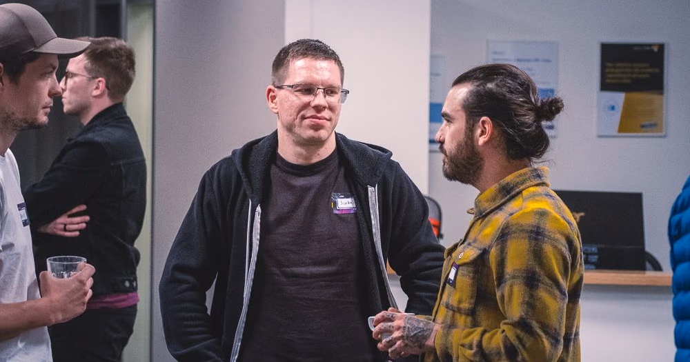Two engineers in a one-to-one conversation with name stickers at an ELC meetup