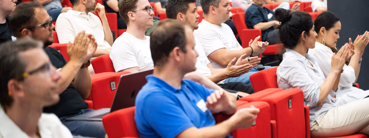 A large audience of engineering leaders in red auditorium seats applauding at an ELC event.