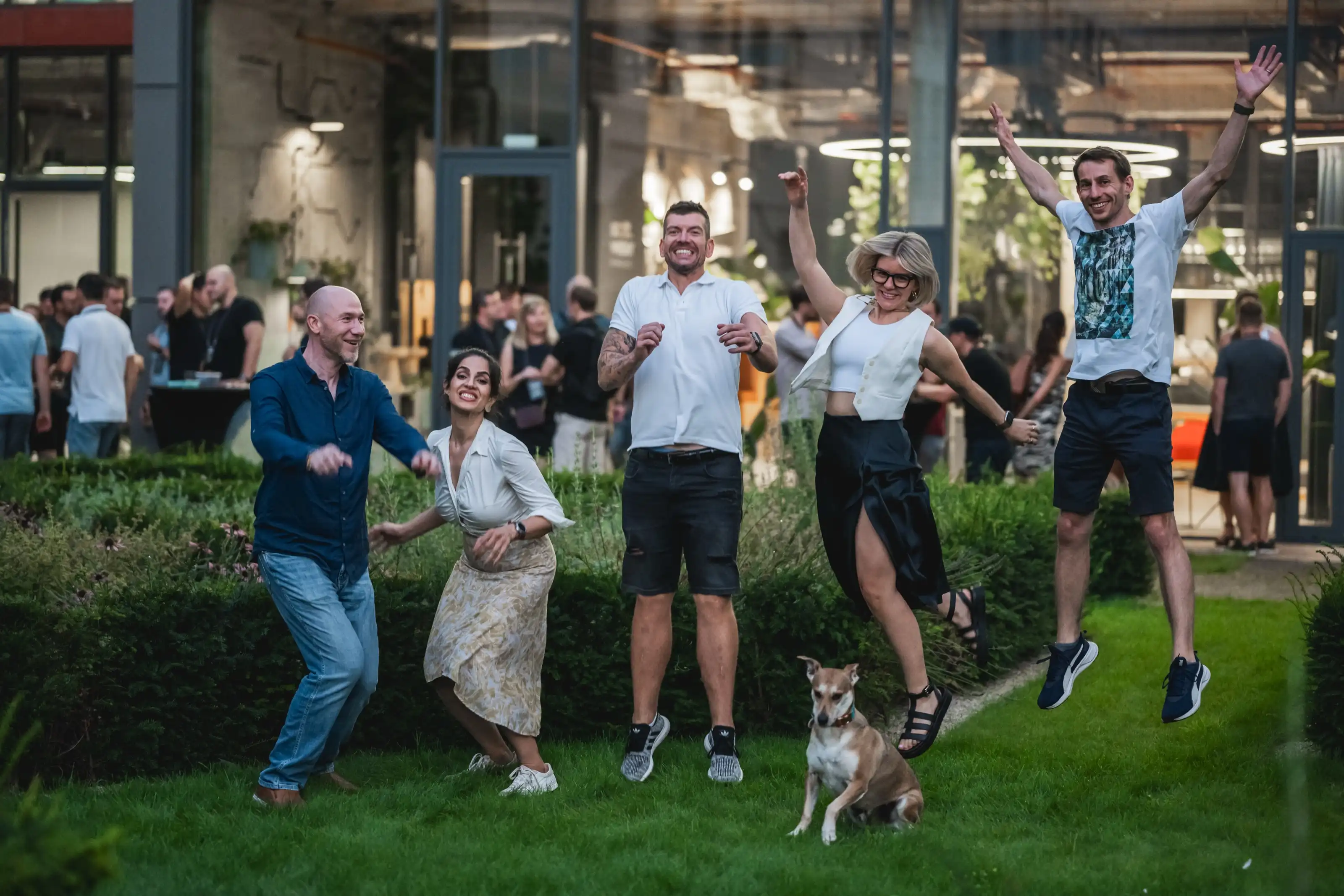 A group of ELC members laughing and jumping together outdoors at dusk during a meetup.